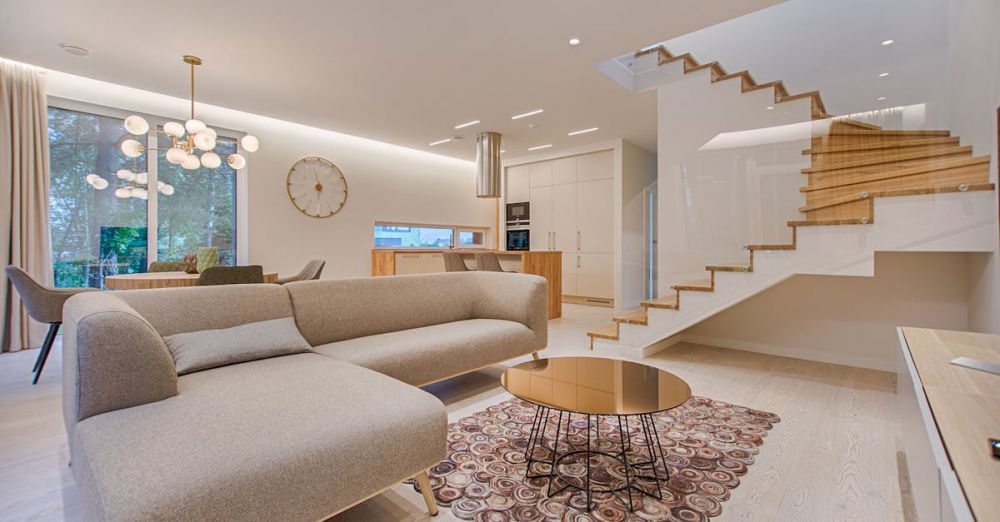 Furniture - Contemporary living room with neutral tones, a sleek sofa, and elegant wooden staircase.