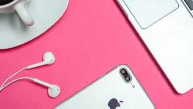 Accessories - A modern workspace with laptop, smartphone, and coffee cup on a vibrant pink background.