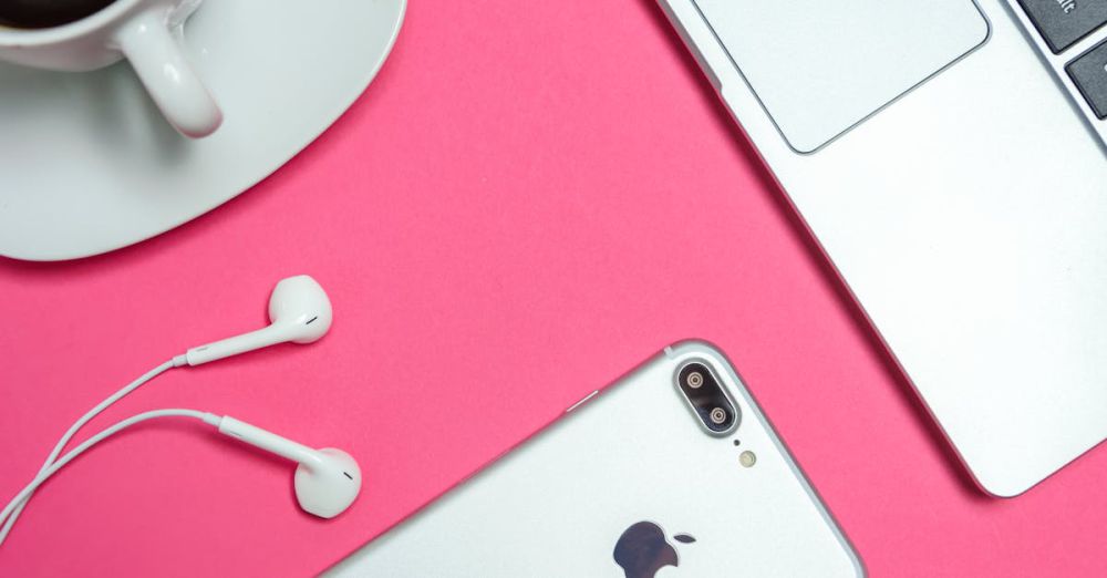 Accessories - A modern workspace with laptop, smartphone, and coffee cup on a vibrant pink background.