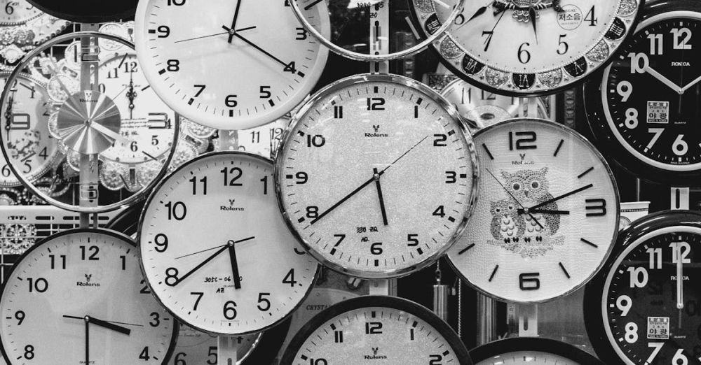 Clocks - A black and white image displaying a diverse array of vintage wall clocks.