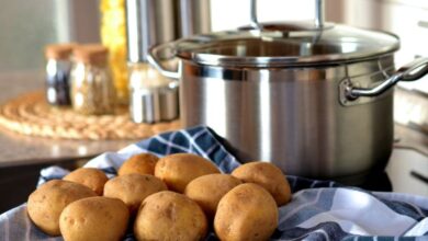 Cookware - Fresh potatoes on cloth beside a stainless pot, ready for cooking in a modern kitchen.