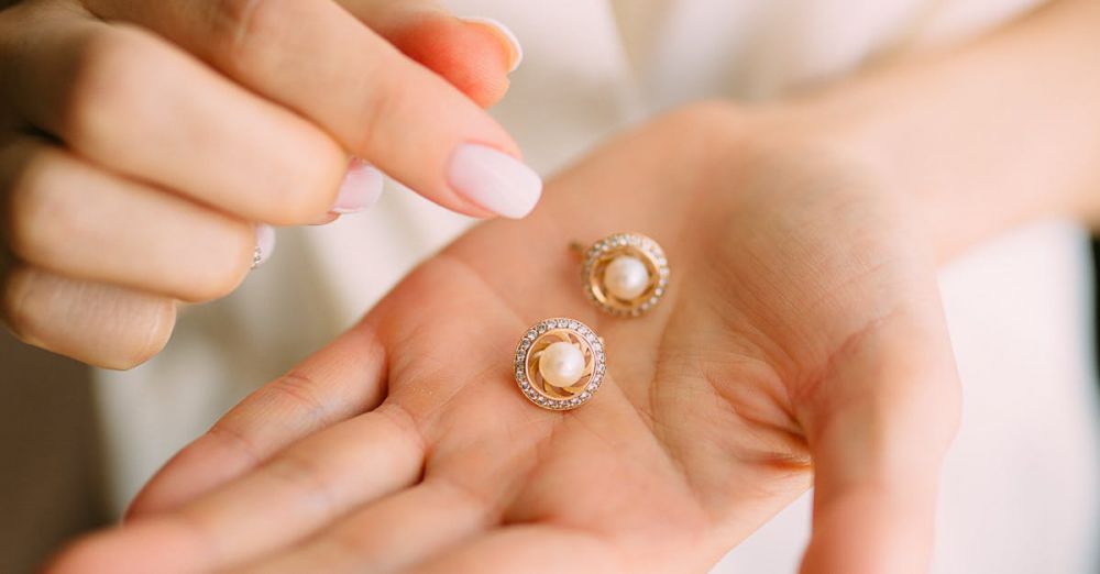 Earrings - Close-up of elegant pearl earrings held in a hand, showcasing luxury jewelry.