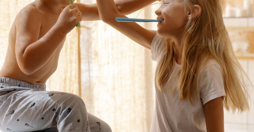 Toothbrushes - Two children sharing a fun and playful moment brushing their teeth in the bathroom.