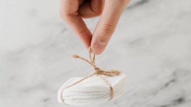 Remover Pads - Hand holding eco-friendly cotton pads tied with jute against marble background.