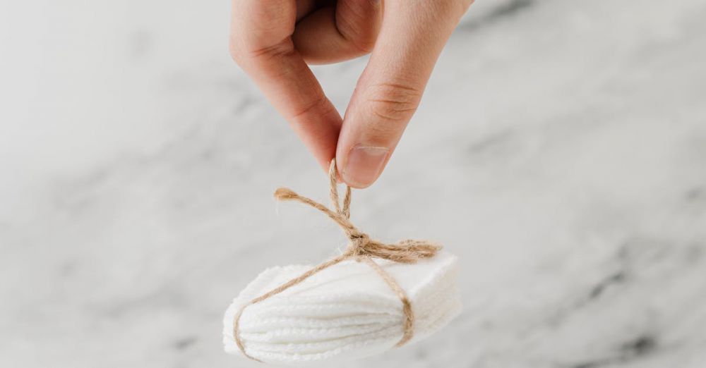 Remover Pads - Hand holding eco-friendly cotton pads tied with jute against marble background.