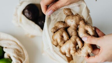 Produce Bags - Hands placing ginger into an eco-friendly reusable net bag on a kitchen counter.