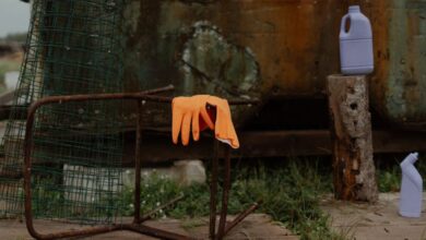 Cleaning Bottles - An outdoor scene featuring a rusted chair, orange latex gloves, and cleaning bottles on a wooden floor.