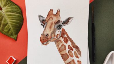 Art - A watercolor painting of a giraffe surrounded by leaves and painting tools.