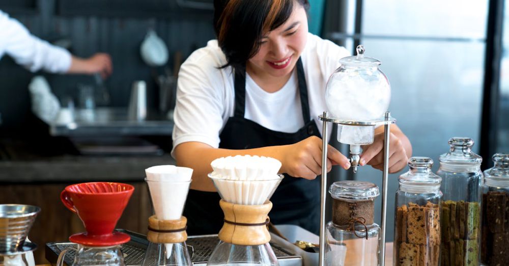 Coffee Filters - Smiling barista making coffee using various equipment in a modern café setting.