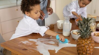 Kitchen Sponges - Children clean up a milk spill on a wooden breakfast table with family nearby, creating a cute and lively morning scene.