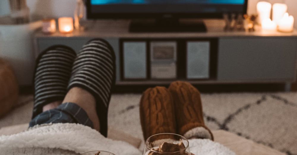 Weighted Blankets - A couple enjoys a cozy movie night with drinks, wrapped in blankets, watching a Harry Potter film on TV.