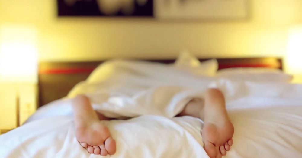 Mattress Toppers - A person relaxing on a bed with feet under white sheets, conveying serenity.