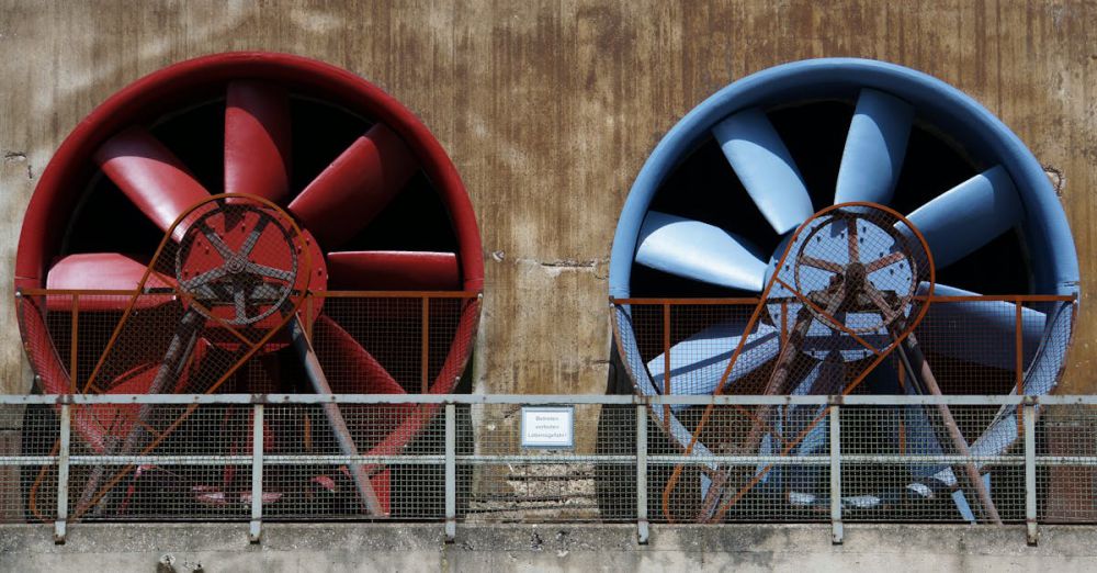 Noise Machines - Close-up of large red and blue industrial fans on a rustic wall showcasing machinery and ventilation.