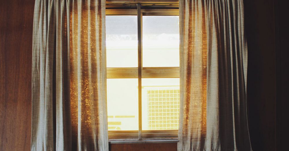 Curtains - Warm sunlight streaming through fabric curtains in a wooden interior setting.