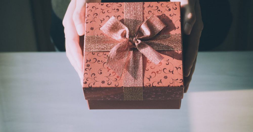 Gifts - Hands presenting a beautifully wrapped gift box with a floral pattern, perfect for any celebration.