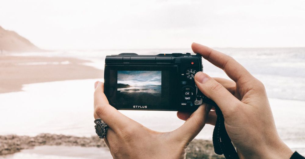 Memory Foam Mattresses - Hands holding a camera capturing a serene beach scene with ocean waves.