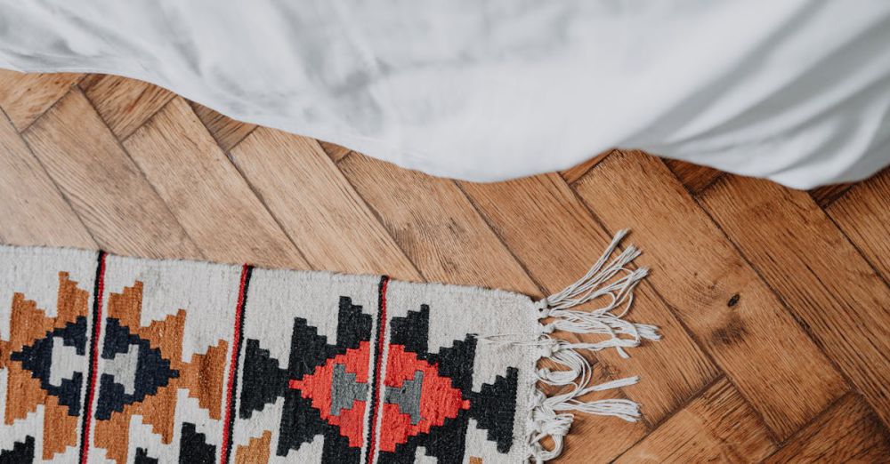 Cotton Linens - Top view of a cozy bedroom showcasing a colorful patterned rug on a wooden floor and pristine white bed linens.