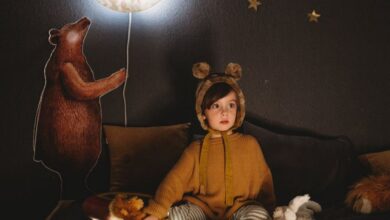 Pajamas - A child in a cozy, magical bedroom with bear decorations and a glowing moon lamp, wearing a costume.