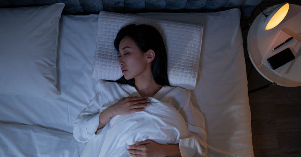 Sleep Environment - Calm and peaceful woman resting in bed under dim lighting, promoting relaxation.