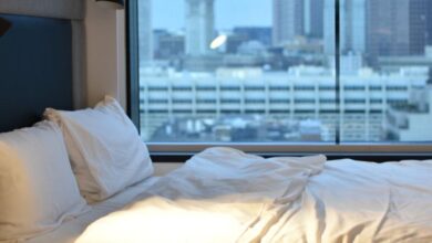 Travel Pillows - Modern hotel room overlooking Boston skyline, featuring luxury bedding.