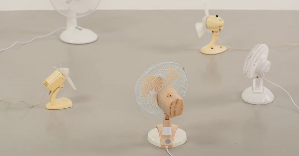 Portable Fans - A variety of small desk fans positioned on a neutral floor showcasing design and color diversity.