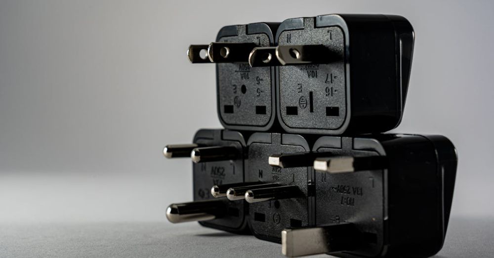 Power Adapters - Close-up of black electrical adapters stacked on a gray background.