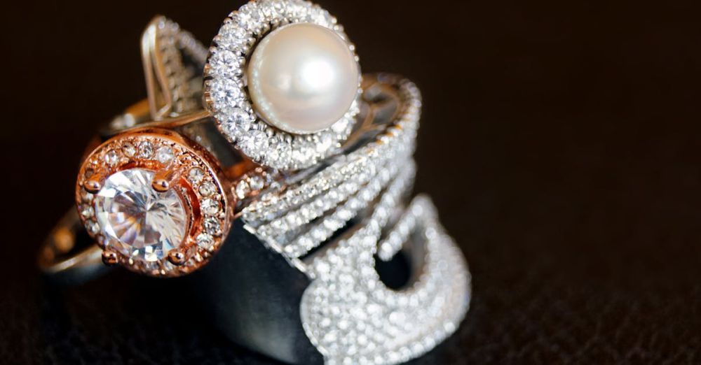 Accessories - Close-up of luxurious pearl and diamond rings with gold accents on a black background.