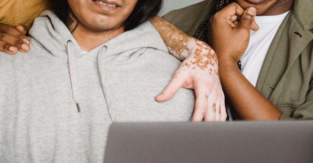 E-Readers - Close-up of diverse individuals collaborating on a laptop indoors, showcasing teamwork and inclusion.