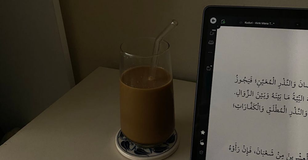 Translation Devices - A tablet displaying Arabic text beside a glass of coffee with straw on a desk.