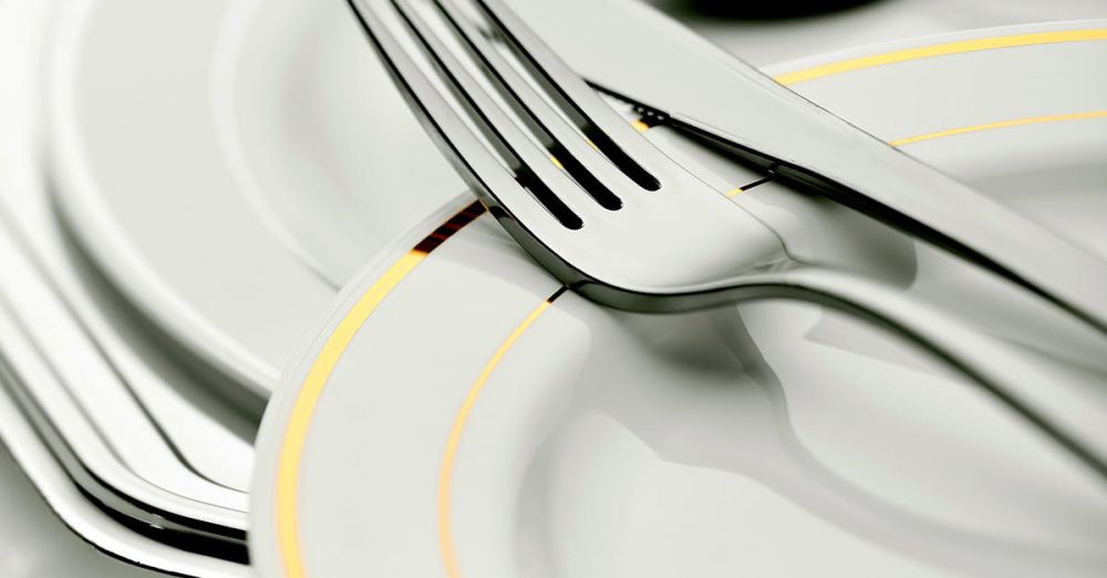 Kitchenware - Close-up of elegant plates and silver cutlery, ideal for dining settings.