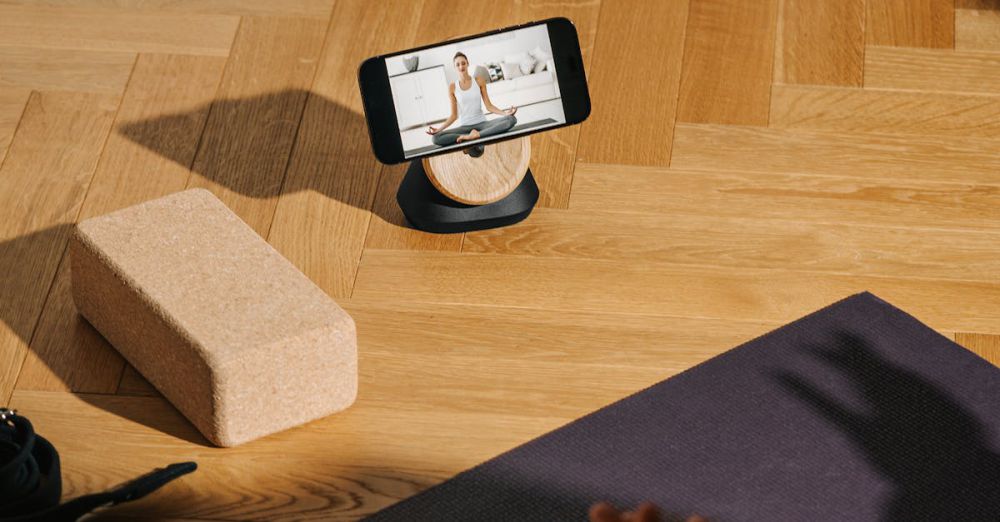 Fitness Streaming - A serene home yoga setup with phone streaming class and mat.