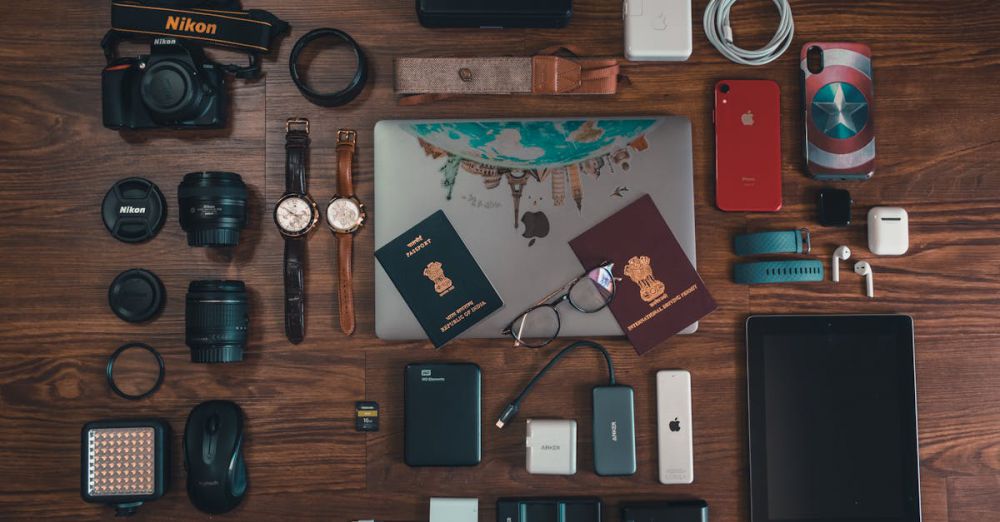 Power Banks - Flat lay of travel essentials including gadgets, passports, and camera on wooden surface.