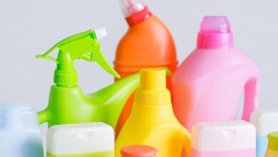 Cleaning Kits - Composition of different colorful plastic containers with detergents for disinfect and daily routine placed on table against white background in room