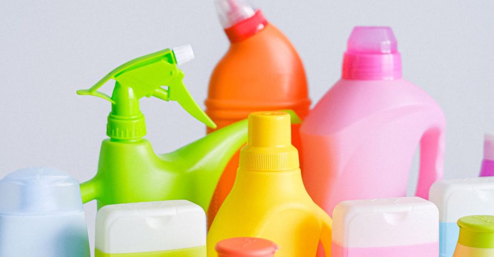 Cleaning Kits - Composition of different colorful plastic containers with detergents for disinfect and daily routine placed on table against white background in room