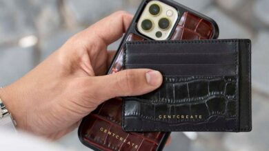 Phone Holders - Person holding an iPhone with a black leather card holder on a paved street.