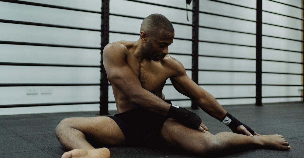 Arm Bands - A shirtless man performing a flexibility stretch on a gym floor.