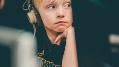 Headsets - Young blonde boy wearing headphones, focusing on a computer screen indoors.