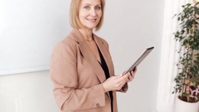 Smart Rings - Middle-aged woman in brown blazer smiling while holding a tablet indoors.