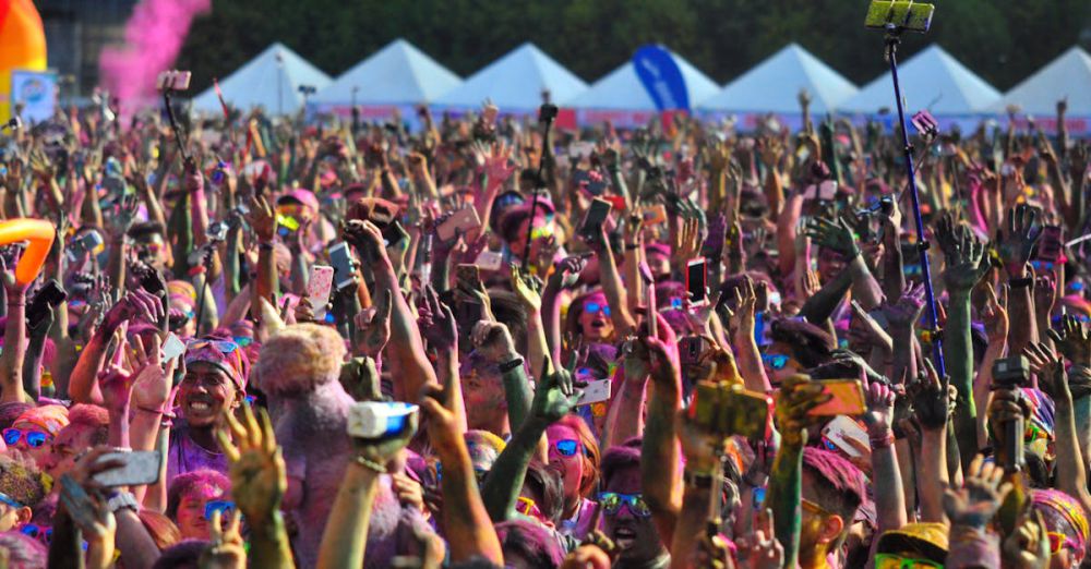 Selfie Sticks - A lively crowd celebrating with colors at a festival in Manila, Philippines.