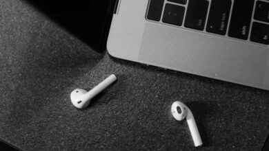 Bluetooth Keyboards - Black and white image of wireless earbuds and laptop, top view.