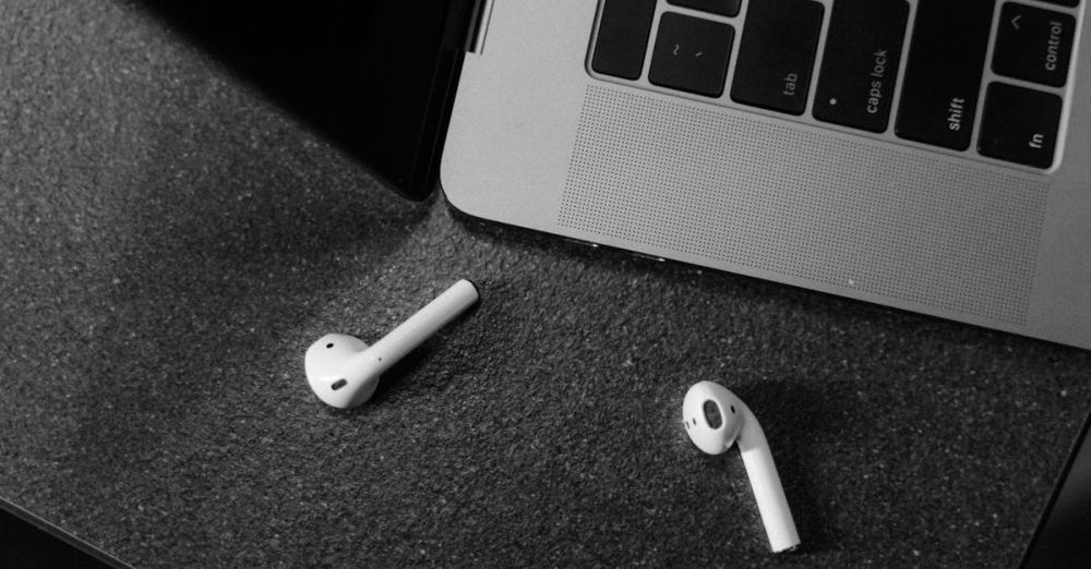 Bluetooth Keyboards - Black and white image of wireless earbuds and laptop, top view.