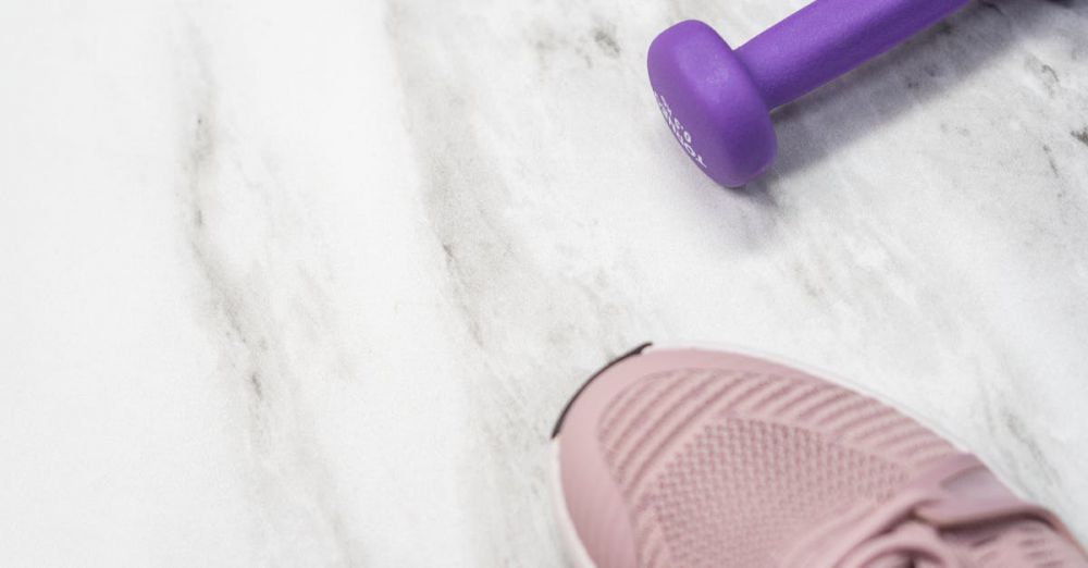 Fitness Bands - Flat lay of pastel pink fitness gear including sneakers and dumbbells on marble texture.