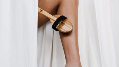 Exfoliators - A person exfoliating their leg with a bamboo brush, promoting eco-friendly skincare.