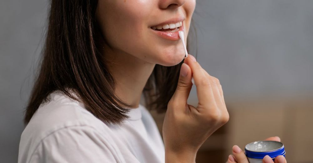 Lip Balms - Woman in a white shirt applies lip balm with a smile, showcasing a skincare routine.