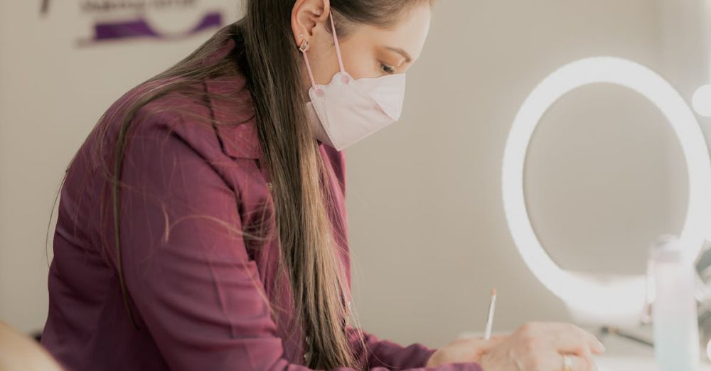 Skincare Kits - Makeup artist wearing mask arranging cosmetics in studio with illuminated mirror.