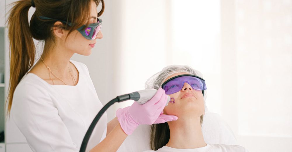 Skin Resurfacing - A cosmetologist performing laser treatment on a woman in a clinic setting.