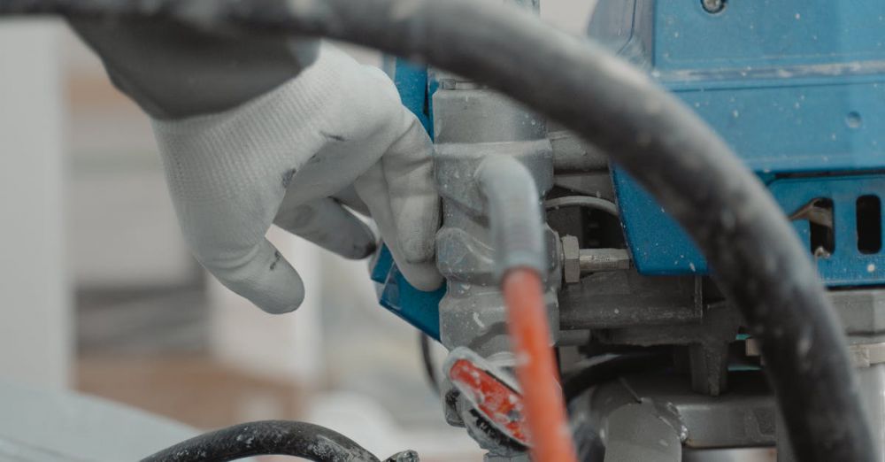 Paint Sprayers - Man wearing gloves operating a paint machine during renovation, featuring hoses and equipment.