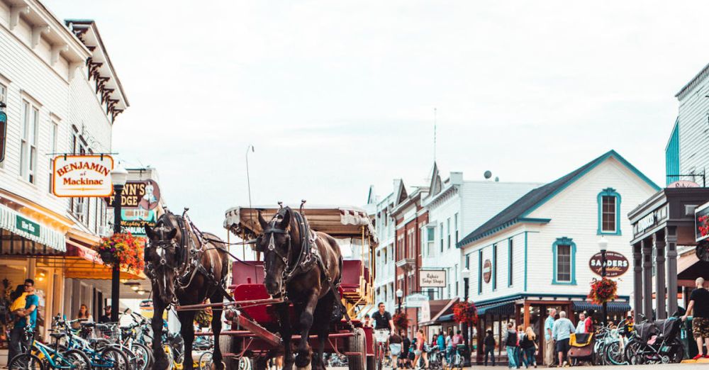 Sanders - A bustling Mackinac Island street scene featuring a horse-drawn carriage and vibrant architecture.