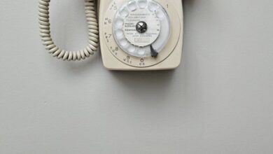 Rotary Tools - Vintage cream rotary dial telephone mounted on a plain wall, classic retro style.