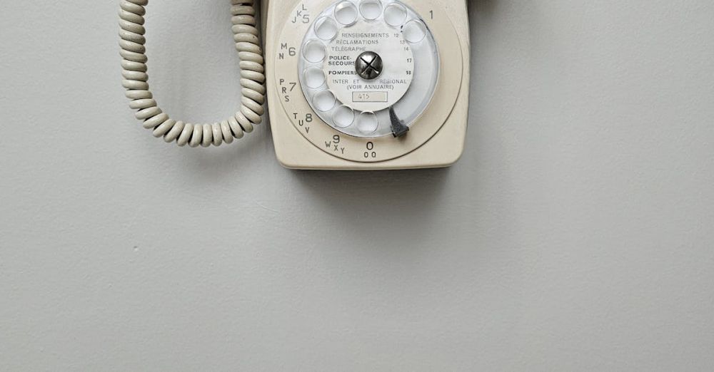 Rotary Tools - Vintage cream rotary dial telephone mounted on a plain wall, classic retro style.